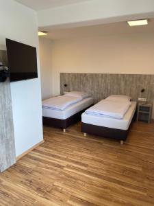 a room with two beds and a flat screen tv at Boardinghouse-Heuchelhof in Würzburg