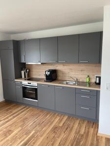 a kitchen with gray cabinets and a wooden floor at Boardinghouse-Heuchelhof in Würzburg