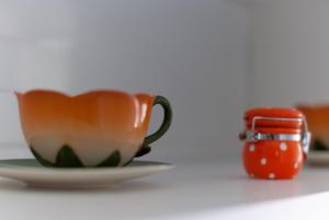 an orange coffee cup sitting on a plate next to a candle at B&B Tor Di Lupo in Mattinata