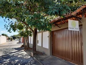 a building with a gate and a tree next to a street at Pousada Sempre Viva in São João Batista do Glória