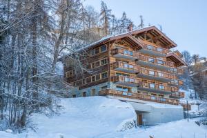 ein großes Holzgebäude im Schnee in der Unterkunft Apartment La Forêt 2 - Spa access in Nendaz