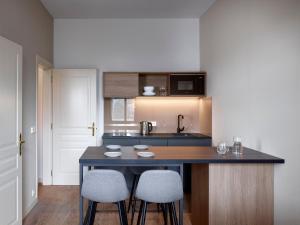 a kitchen with a counter with two stools and a sink at Franz BY ZEITRAUM in Prague