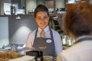 a woman standing in a kitchen preparing food at Maldron Hotel Manchester City Centre in Manchester