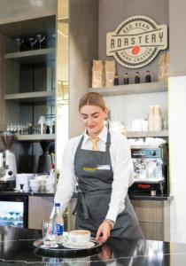 a woman standing in a kitchen with a plate of food at Maldron Hotel Manchester City Centre in Manchester