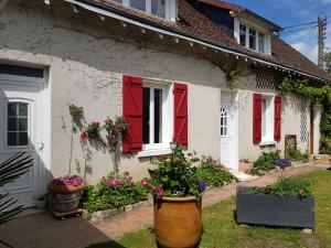 une maison avec des volets rouges et des fleurs devant elle dans l'établissement 18 châteaux et Beauval sur un rayon de 30 km, à Saint-Georges-sur-Cher