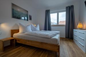 a bedroom with a bed with a dresser and a window at Apartment Nora in Ehrwald