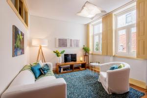 a living room with two white chairs and a tv at São Miguel Apartments in Porto