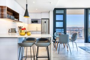 una cocina con encimera con sillas y una isla de cocina en Always-Power Luxury Sky Retreat, en Ciudad del Cabo