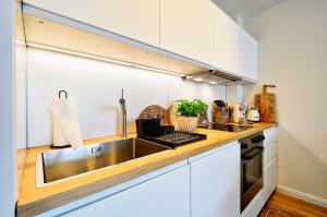 a kitchen with a stainless steel sink and white cabinets at Ferienwohnung Hafenliebe, Villa Vilmblick mit Meerblick in Lauterbach