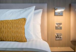 a bed with white sheets and a yellow pillow at Maldron Hotel Manchester City Centre in Manchester