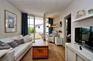 ein Wohnzimmer mit einem weißen Sofa und einem TV in der Unterkunft Ferienwohnung Hafenliebe, Villa Vilmblick mit Meerblick in Lauterbach
