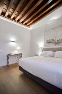 a white bedroom with a large bed and a desk at Hospedium Hotel Posada de la Silleria in Toledo