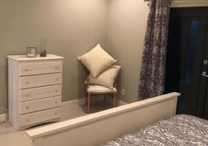 een slaapkamer met een bed, een dressoir en een stoel bij Luxury Venetian Condo in Nassau