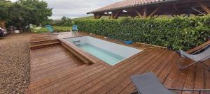 a swimming pool on a wooden deck with two chairs at La Maison des Vignes in Charentay