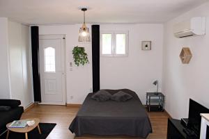a bedroom with a bed and a living room at Appartement le Tilleul - Apparts Cosy in Saint-Pons
