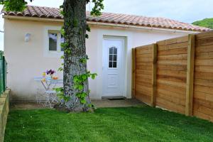 a fence in front of a house with a tree at Appartement le Tilleul - Apparts Cosy in Saint-Pons