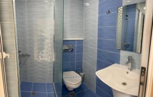 a blue tiled bathroom with a toilet and a sink at Гостоприемница Георги in Kalofer