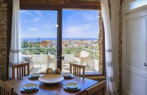 een eetkamer met een tafel en een groot raam bij Giardini Del Golfo in Balestrate