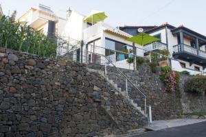 a stone retaining wall with a building and green umbrellas at Crystal House in Calheta