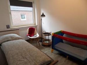 a bedroom with a bed and a chair and a window at Apartment Zentrum in Bad Zwischenahn