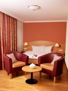 ein Hotelzimmer mit einem Bett und zwei Stühlen in der Unterkunft Golf- und Landhotel Anetseder in Thyrnau