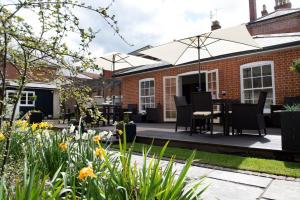 a patio with chairs and an umbrella in a garden at East Walls Hotel in Chichester