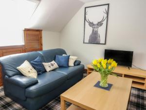 una sala de estar con un sofá azul y un jarrón de flores en Upper Brackendale, en Taynuilt