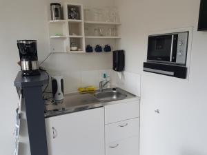 eine kleine Küche mit einer Spüle und einer Mikrowelle in der Unterkunft Achter de Beukenboom in Roden