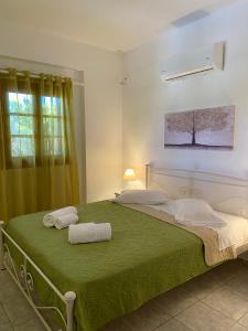 Un dormitorio con una cama verde con toallas. en Kouremenos Beach Apartments, en Palaikastro