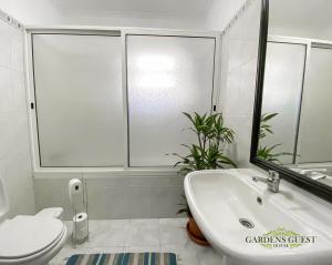 La salle de bains est pourvue d'un lavabo blanc et de toilettes. dans l'établissement Gardens Guest House, à São Vicente