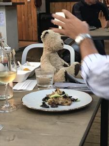 a teddy bear sitting on a table with a plate of food at L'Hotel du Garage des Cevennes in Anduze