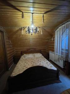 Cama en habitación de madera con lámpara de araña en Садиба у Попа en Lumshory