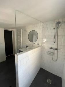 een wit betegelde badkamer met een wastafel en een spiegel bij La Magnanerie in LʼIsle-sur-la-Sorgue