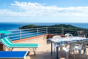 balcone con tavolo, sedie e vista sull'oceano di Villa La Terrazza sul Mare - Goelba a Fetovaia