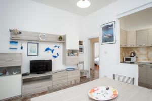 a kitchen and living room with a table and a television at Villa La Terrazza sul Mare - Goelba in Fetovaia