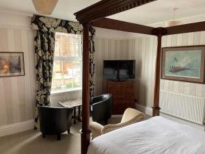 a bedroom with a bed and two chairs and a television at Arundel House in Whitby