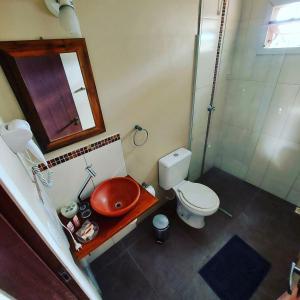 ein Badezimmer mit Toilette, Waschbecken und Spiegel in der Unterkunft Pousada VistaCalma in Praia do Rosa + 21 Fotos