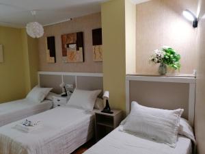 two beds in a room with flowers on the wall at Cuatro Caminos in Sarria