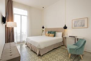 um quarto com uma cama branca e uma cadeira azul em Forget Me Not Barcelona em Barcelona