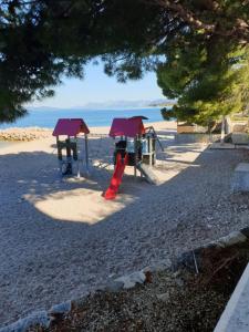 een speeltuin op het strand met de oceaan op de achtergrond bij Apartmani Jolanda in Podgora