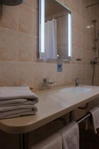 a bathroom with a sink and a mirror and towels at Astoria Hotel in Tuapse