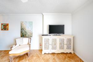 a living room with a tv and a chair at Ocean House in Gulf Shores