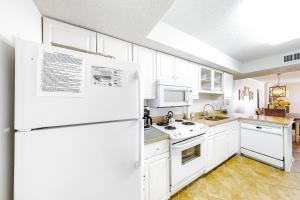 a kitchen with white cabinets and a white refrigerator at Ocean House in Gulf Shores