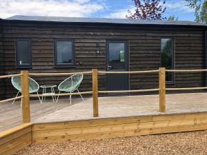 Cabaña de madera con 2 sillas en una terraza en Willow Lodge 2, en North Newton