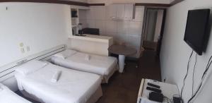 a small room with two beds and a television at Tabajara Flats Praia de Iracema in Fortaleza