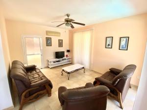 a living room with leather chairs and a tv at Villa Lola in Ayia Napa