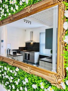 a mirror reflecting a kitchen in a room with white flowers at Monopoly Holiday Home in Blackpool