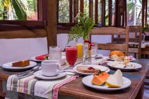 una mesa de madera con platos de comida. en Pousada Refugio da Harmonia, en Ilhabela