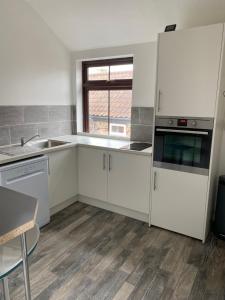 a kitchen with white cabinets and a sink at 1st Floor Flat in Mews in Kessingland