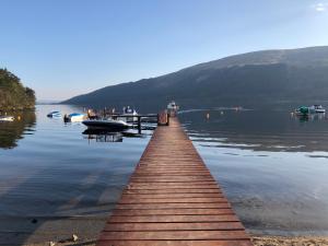 a dock on a lake with boats in the water at Loch Lomond Lodge in Rowardennan